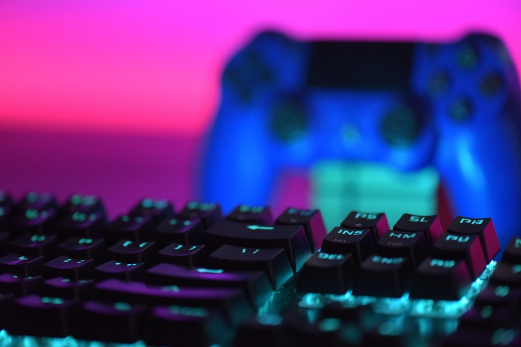A gaming keyboard with a Playstation controller behind it.